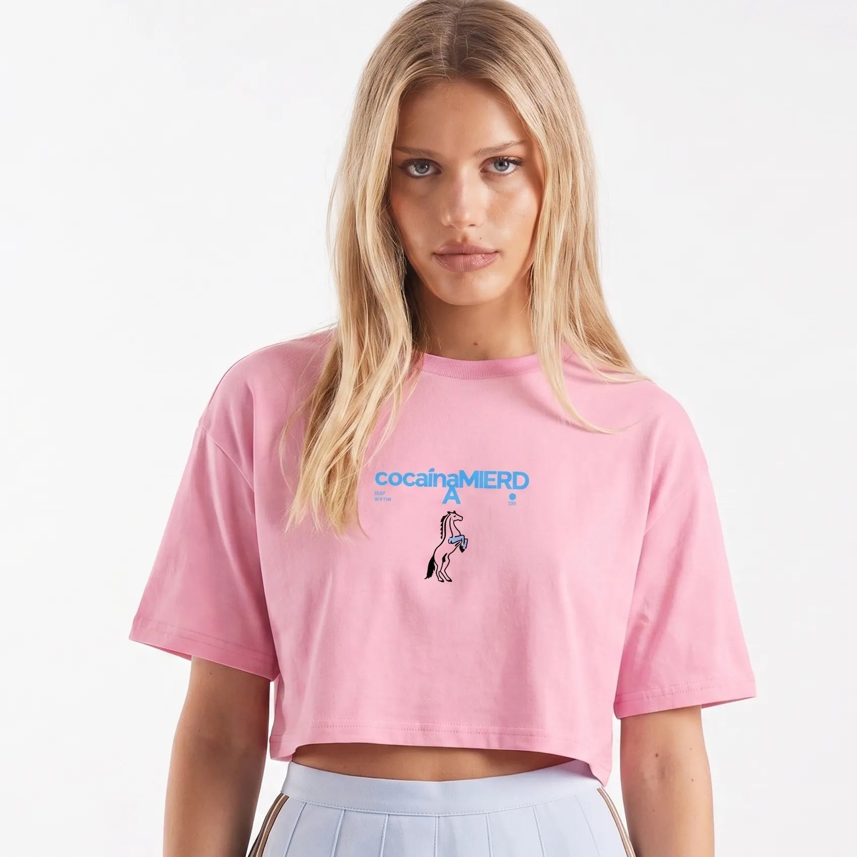 Crop top rosa bubblegum in cotone con scritta blu "cocainamierda" e grafica unicorno, stile streetwear con messaggio forte.